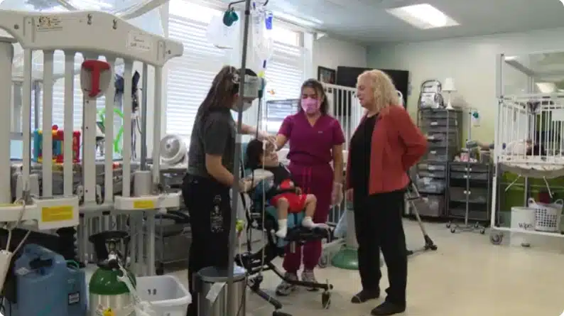 Director and caregivers treating child in wheelchair at Maryville: Center for Children